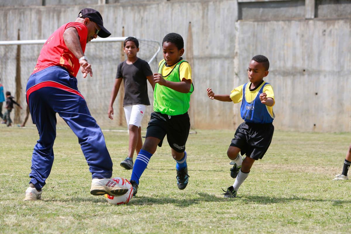 Coach and children playing football together